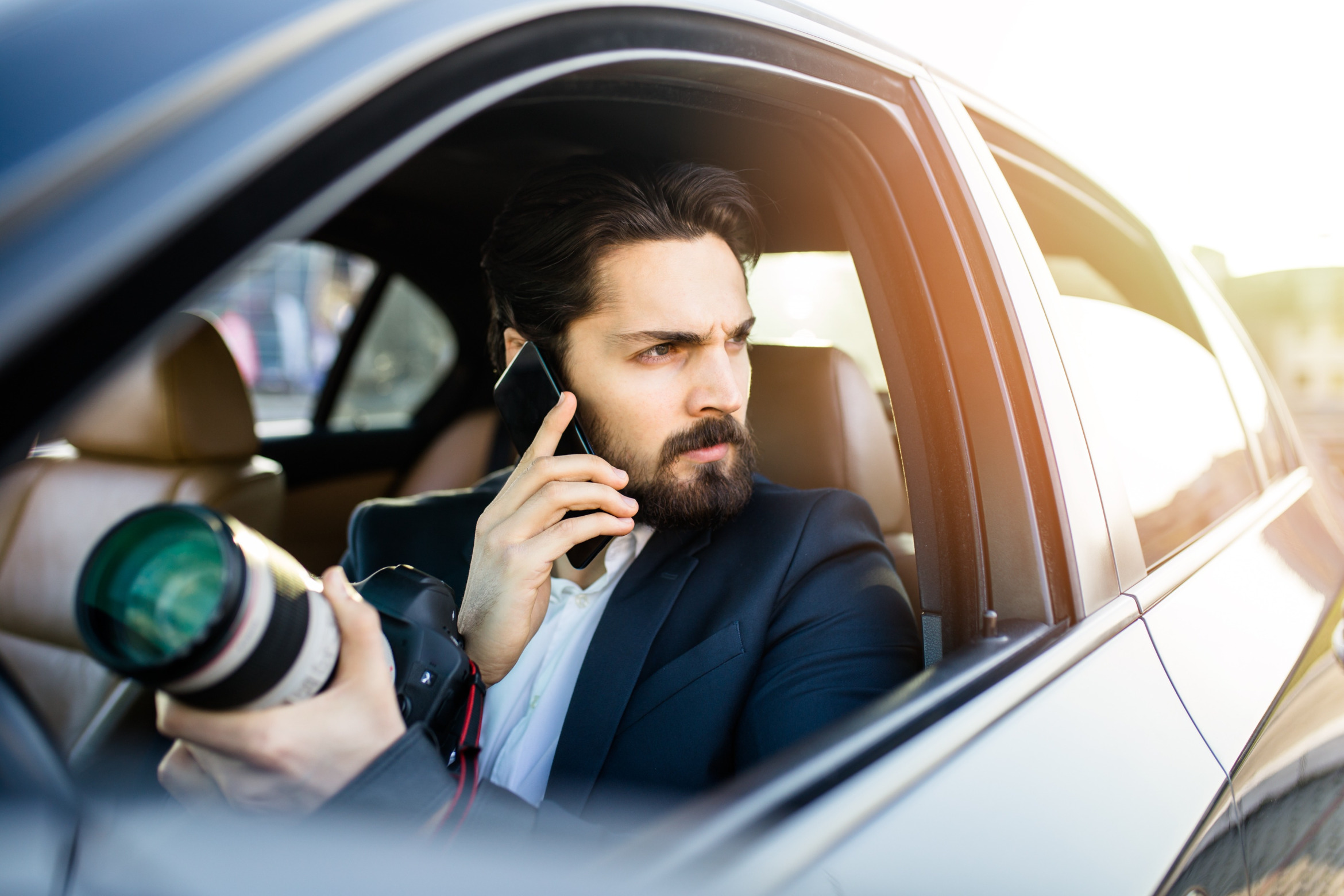 Detektiv mit Kamera telefoniert im Auto; Privatdetektei Soest, Wirtschaftsdetektiv Soest, Privatermittler Soest